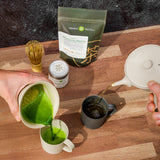 Matcha is poured into a white cup and hojicha tea is poured from a white kyusu into a black tea cup by Nankei Ceramics,