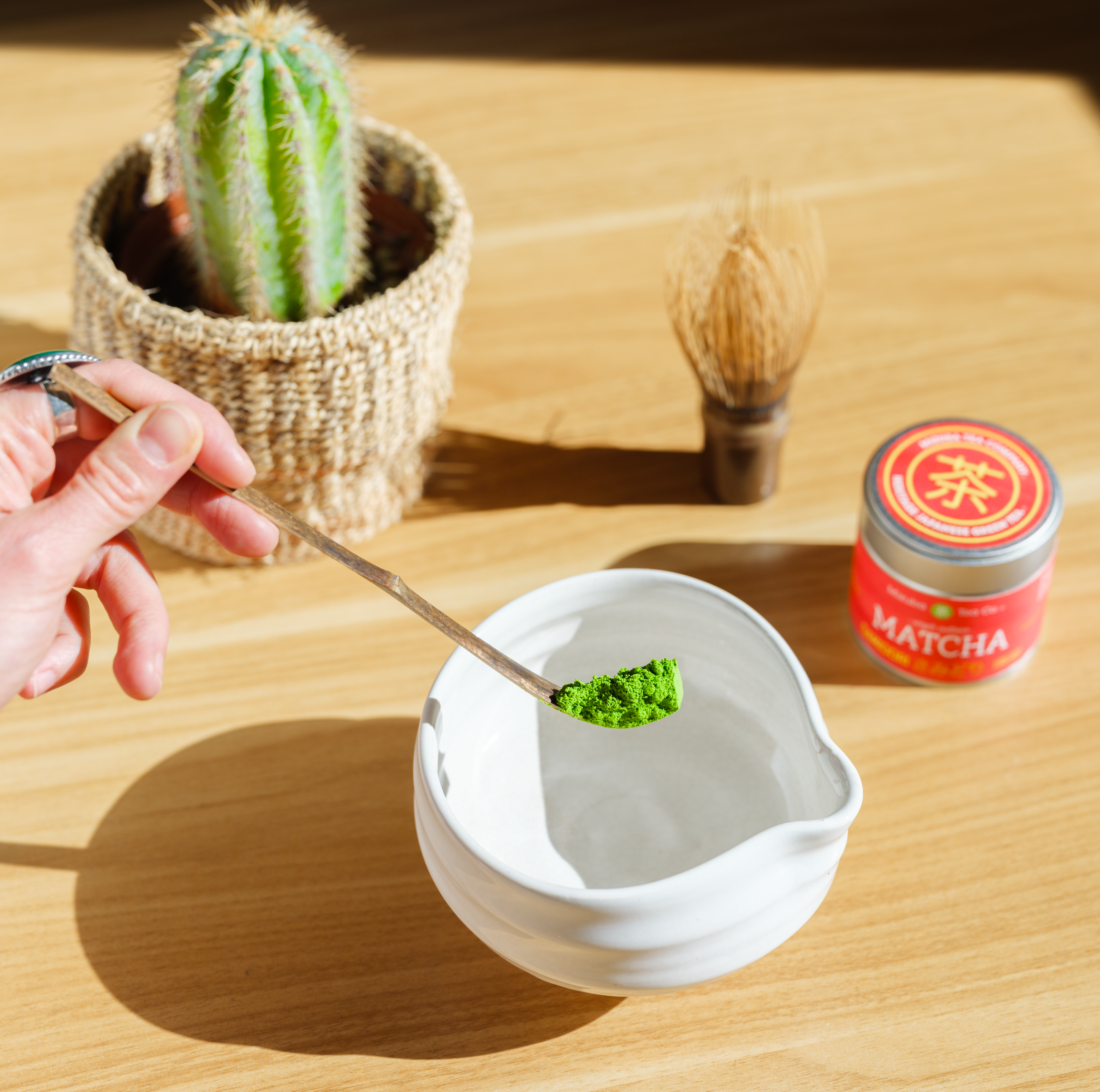 A hand uses a chashaku matcha scoop to lower powdered green tea into a chawan tea bowl – Mizuba Tea Co.