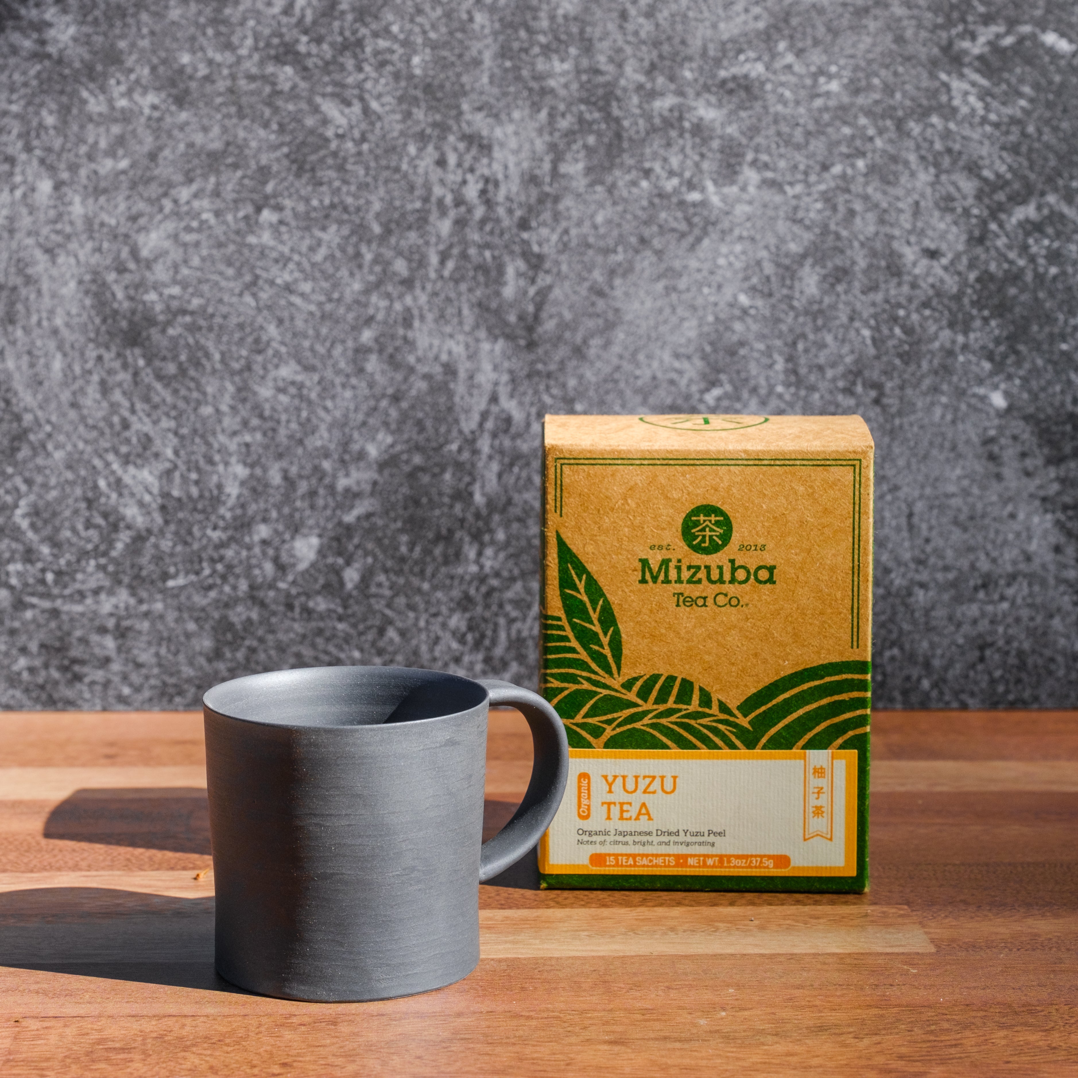 Black ceramic mug with yuzu tea sachets by Mizuba Tea Co.