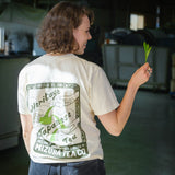 Woman wearing a custom illustrated shirt with Japanese tea design holds a fresh tea leaf from the fields of Japan
