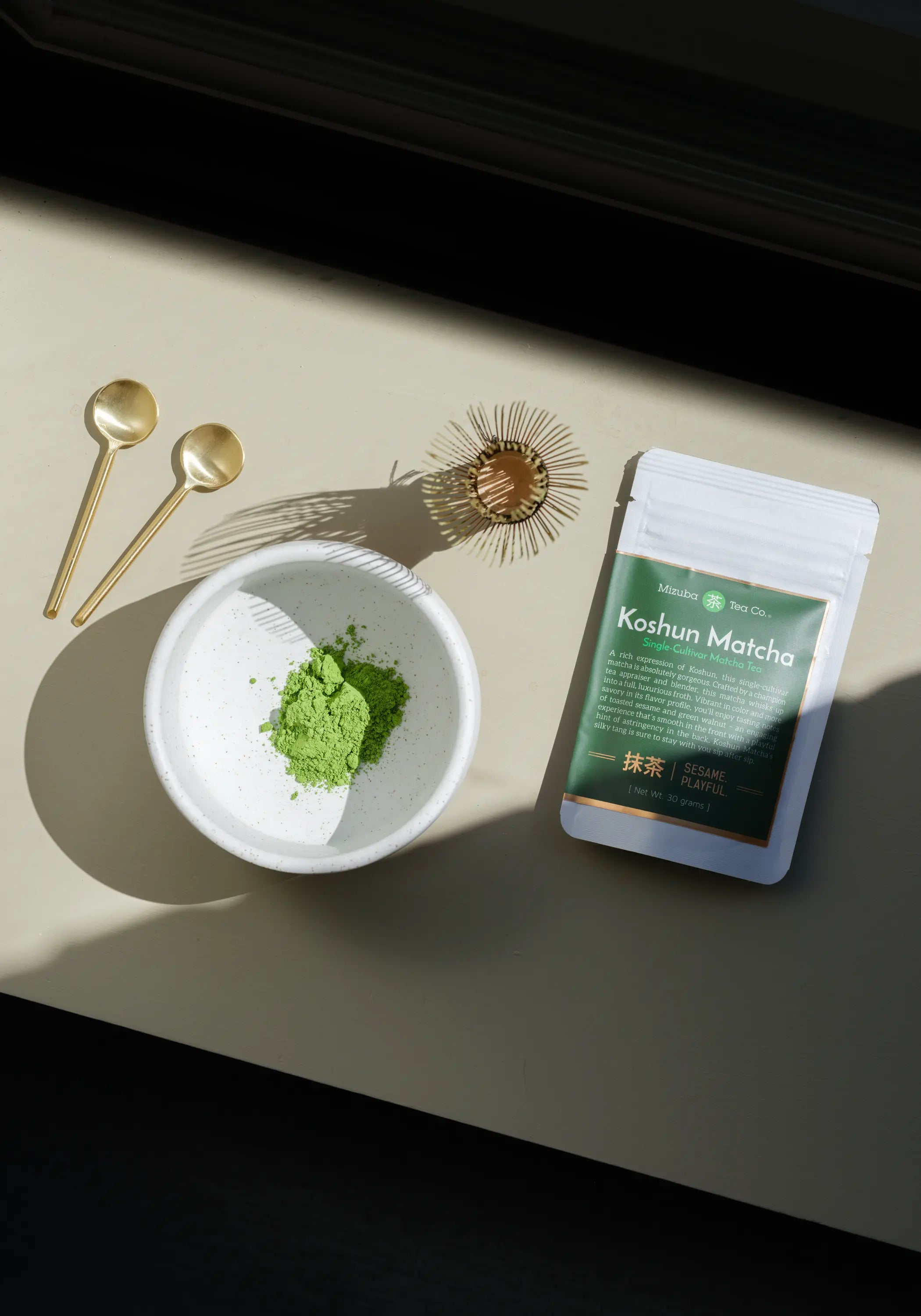 Koshun Matcha powder in a bowl next to a bag of matcha
