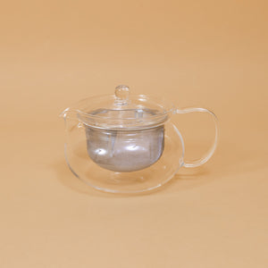 Japanese glass tea pot by Hario sits on a yellow background