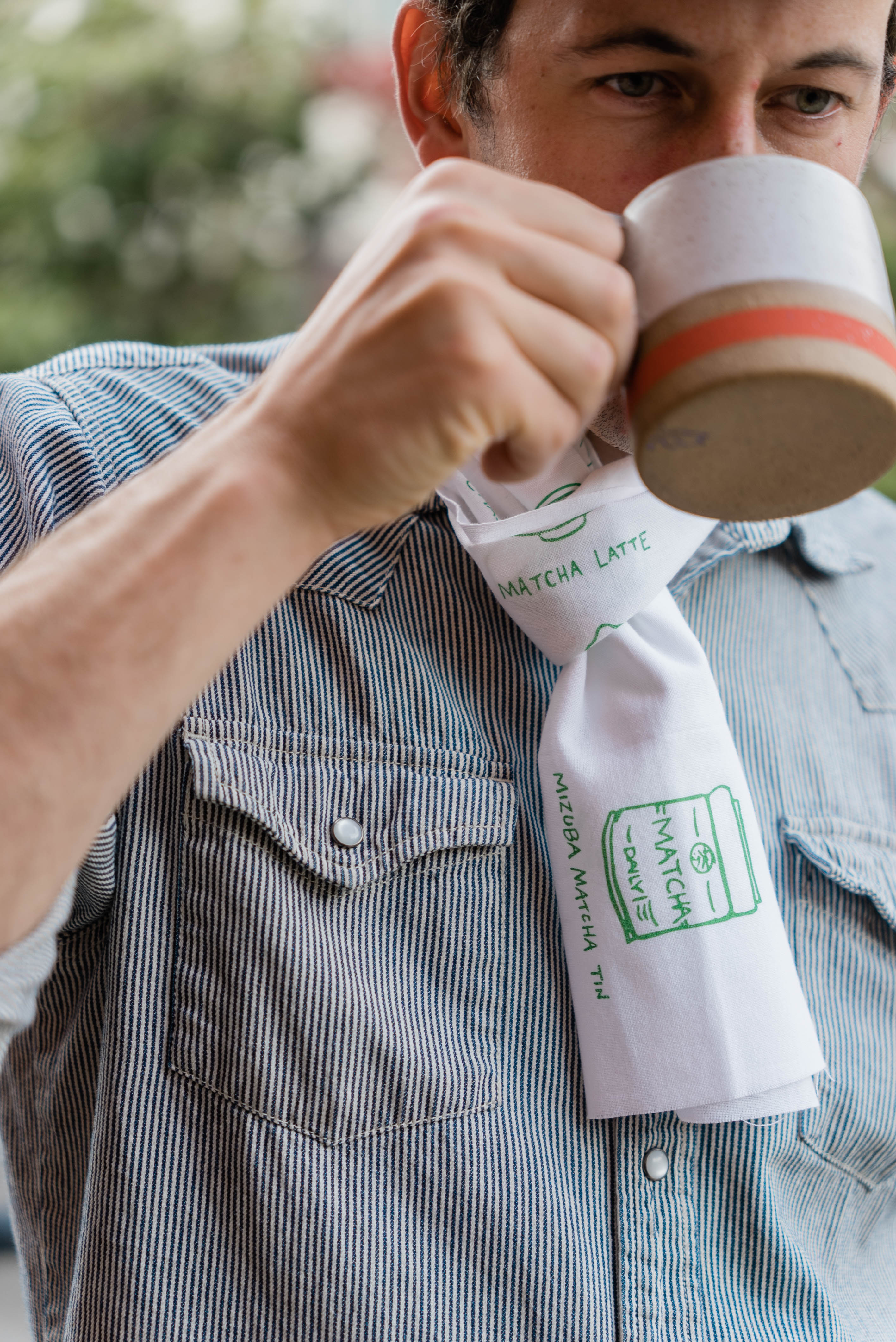 Man drinking tea wearing a Mizuba Tea Co. Tenugui