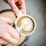 Two hands pouring a hojicha roasted green tea latte in a coffee shop - Mizuba Tea Co.