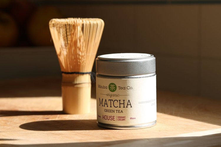 Bamboo whisk next to branded Mizuba Matcha tin