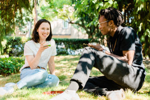 Woman and Man drink matcha green tea together on a grassy lawn in the shade