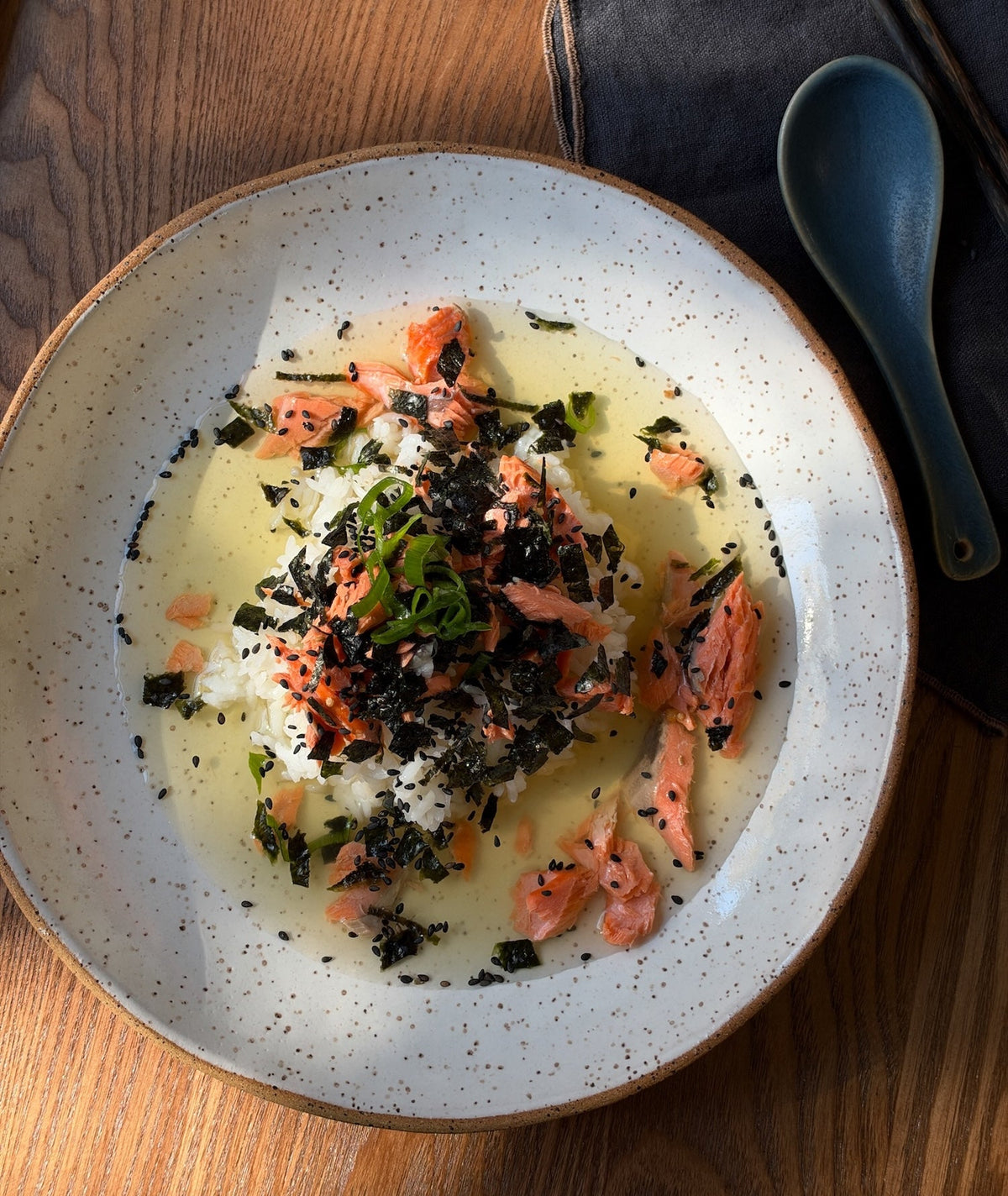A bowl of ochazuke topped with salmon, nori, and green onions