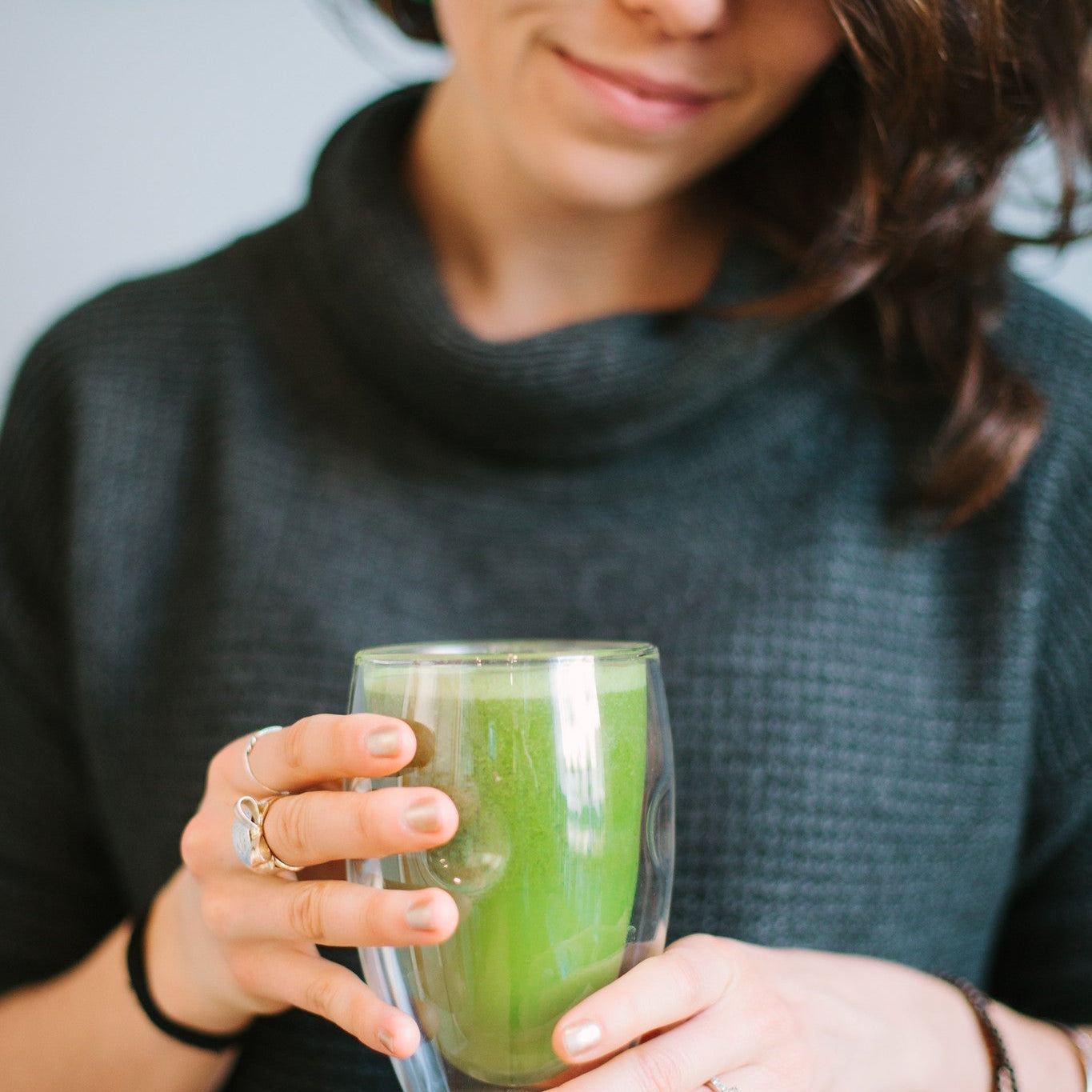A woman holding a matcha green tea after making it