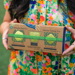 A woman in a colorful floral dress holds a box labeled Mizuba Tea Co. Matcha Tasting Trio. 