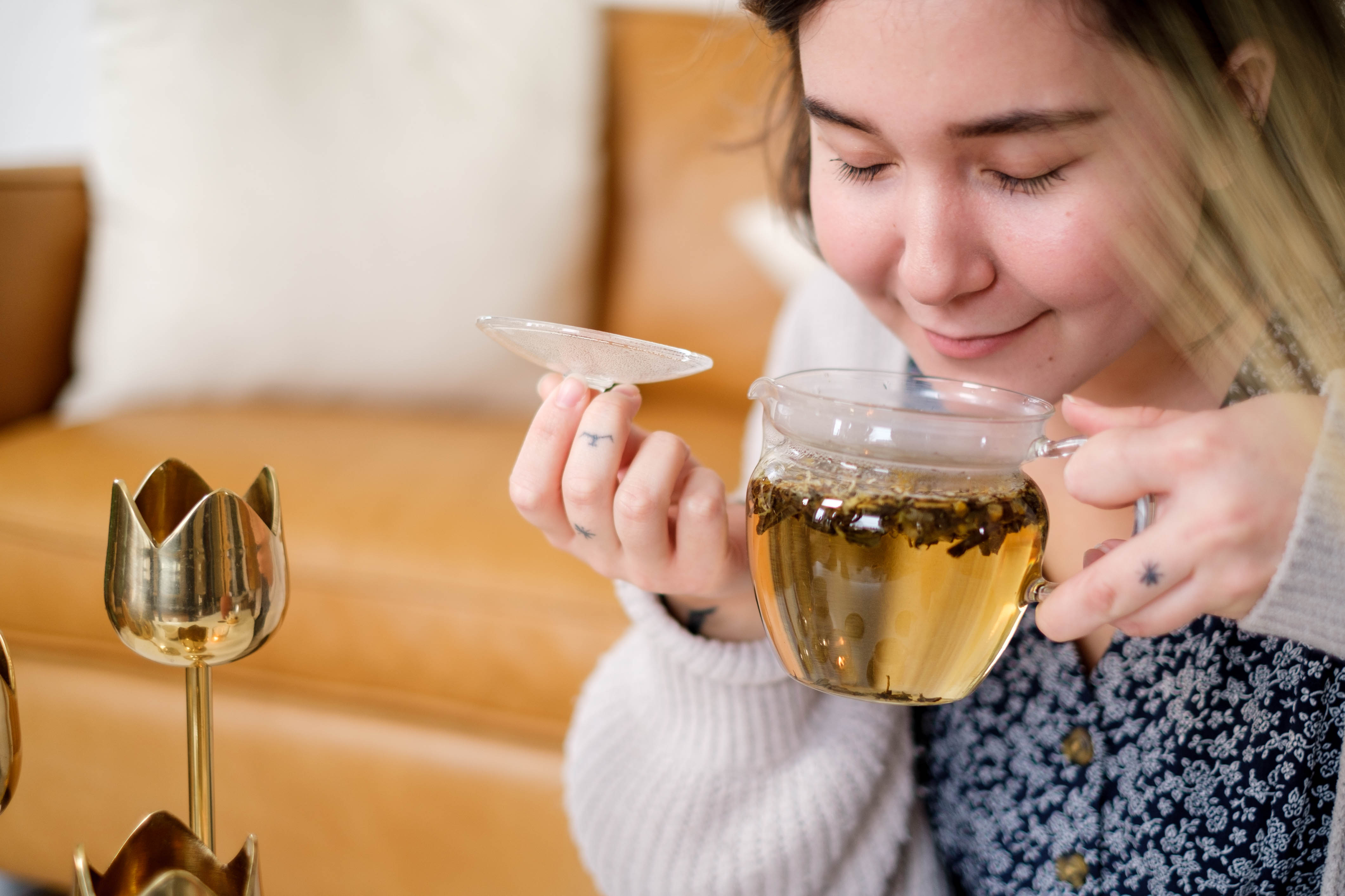 Woman enjoys smelling Mizuba Tea Chamomile Hojicha brewing in a glass teapot from Japan