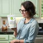 Woman holding a package of Organic Signature Matcha Green Tea by Mizuba Tea Co. in a kitchen