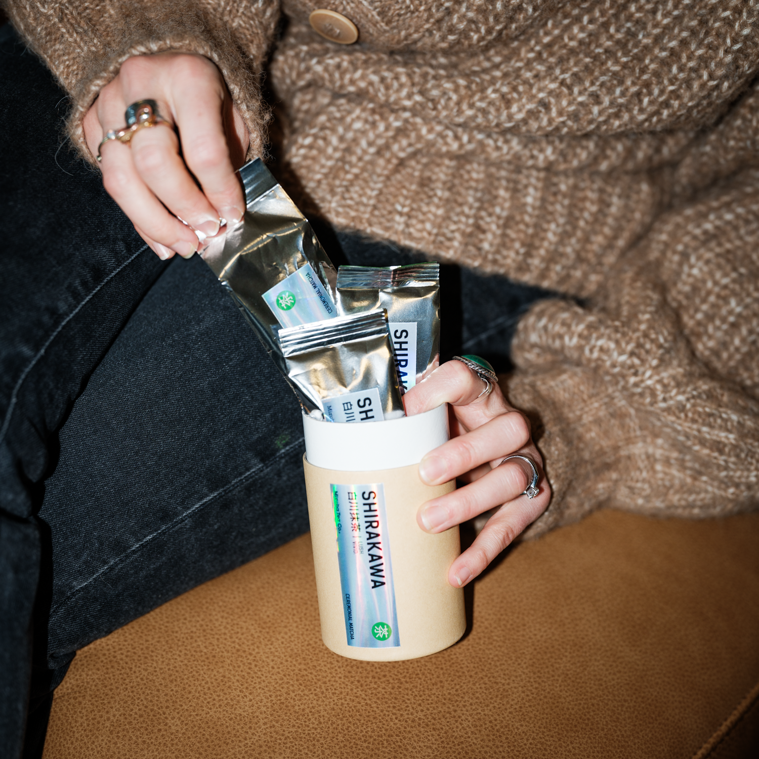 Person holding a container with Mizuba Tea Company's Shirakawa Matcha Subscription from Uji.