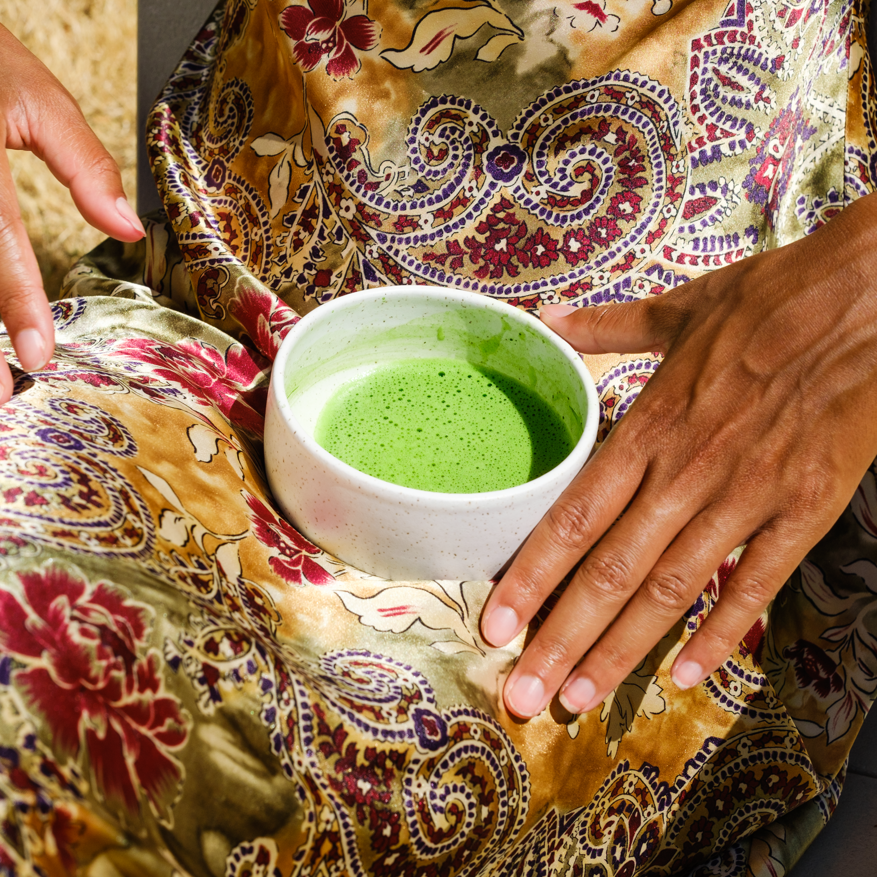 Bowl of frothy Mizuba matcha green tea rests in a woman's lap.