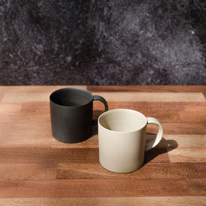 Two unglazed tea cups by Nankei Pottery  – one black and one white