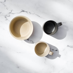 Overhead shot of Nankei Pottery Japanese ceramics. One matcha bowl, one black teacup, and one white teacup
