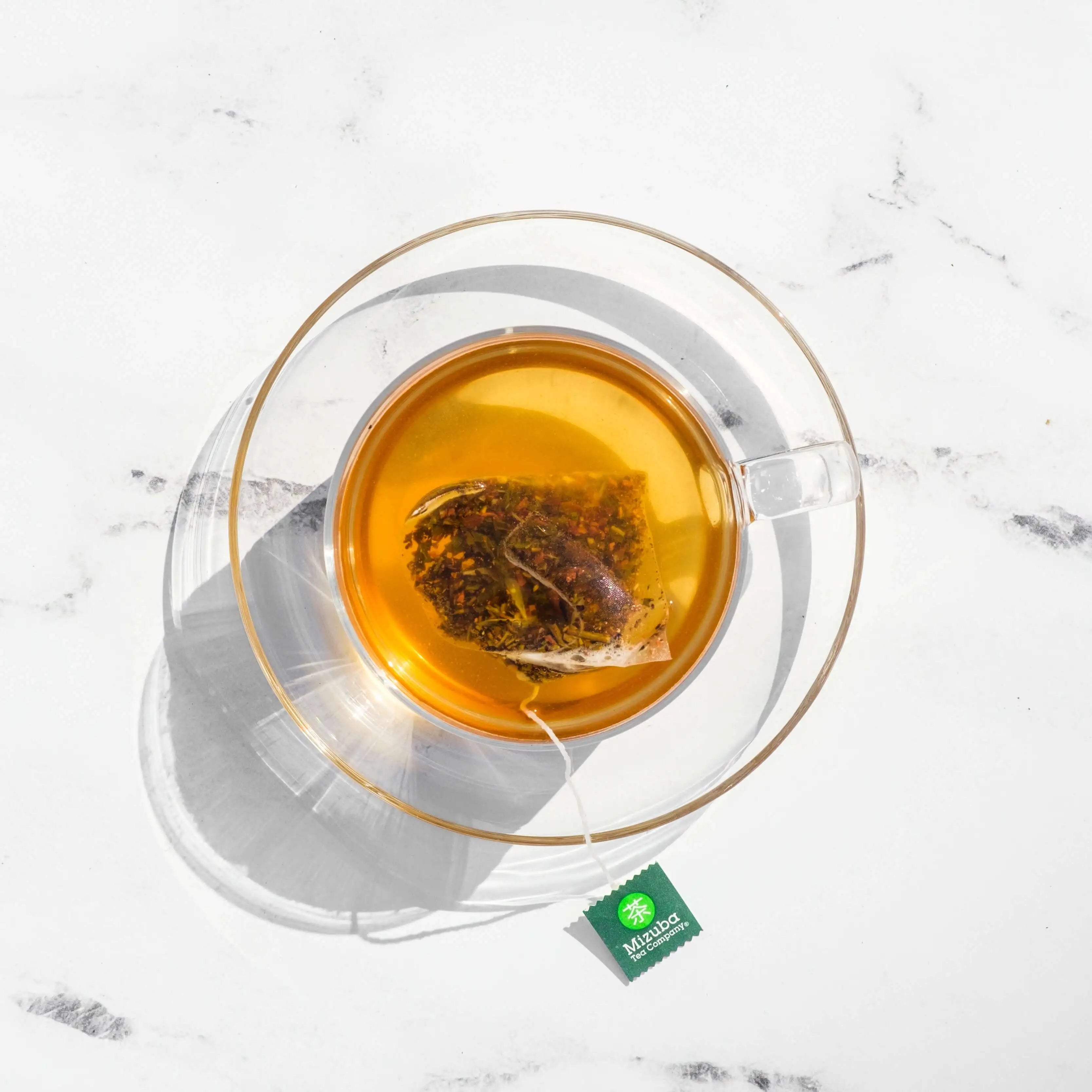 Mizuba Tea Co. Cacao Hojicha sachet tea bag brews in a glass tea cup.