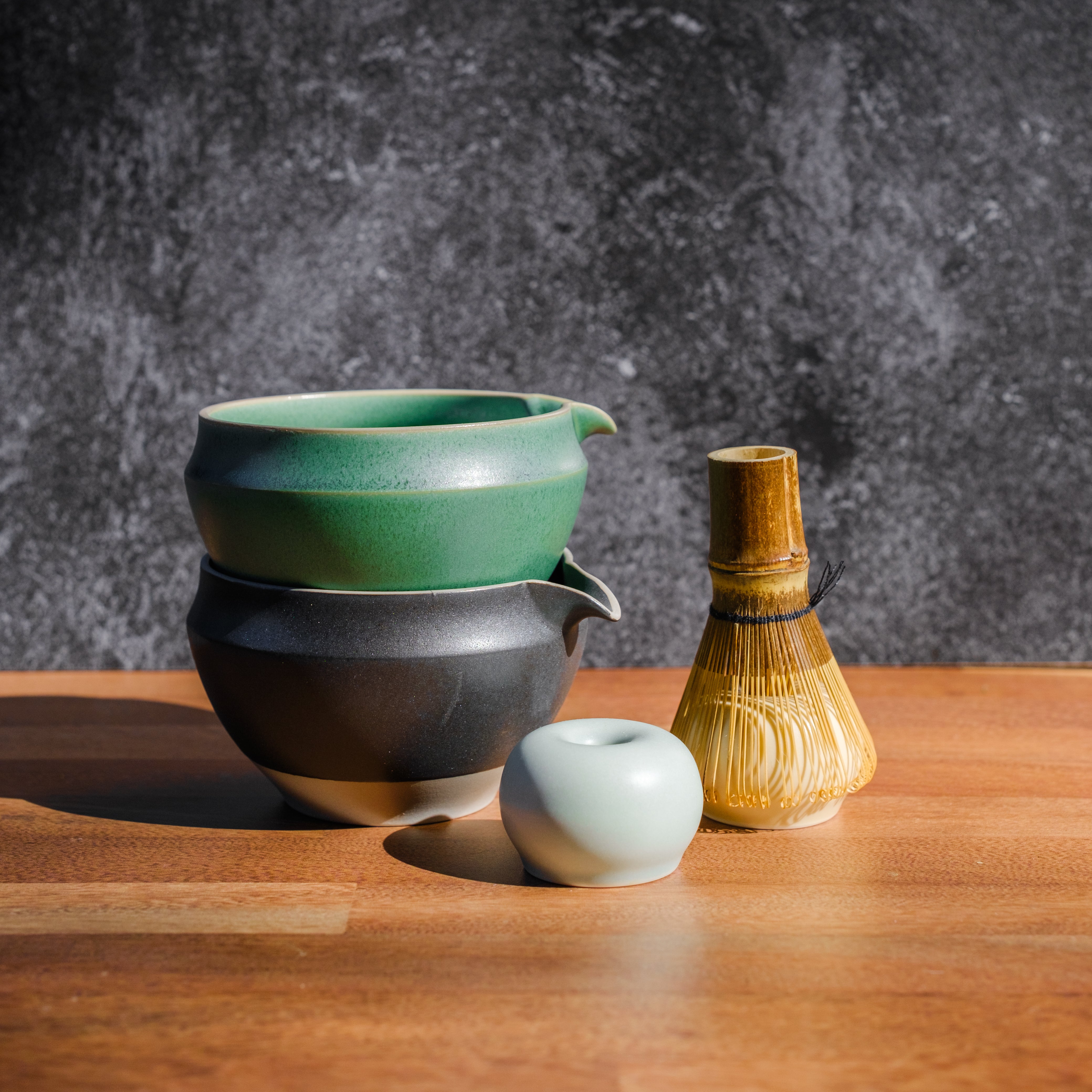 Ceramic matcha green tea chawan bowls by origami stacked next to a matcha whisk stand and chasen bamboo whisk