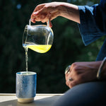Pouring fresh 2025 Japanese shincha green tea into a Asemi yunomi blue ceramic cup. 