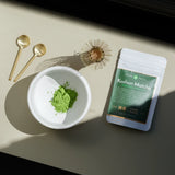 Koshun Matcha powder in a bowl next to a bag of matcha
