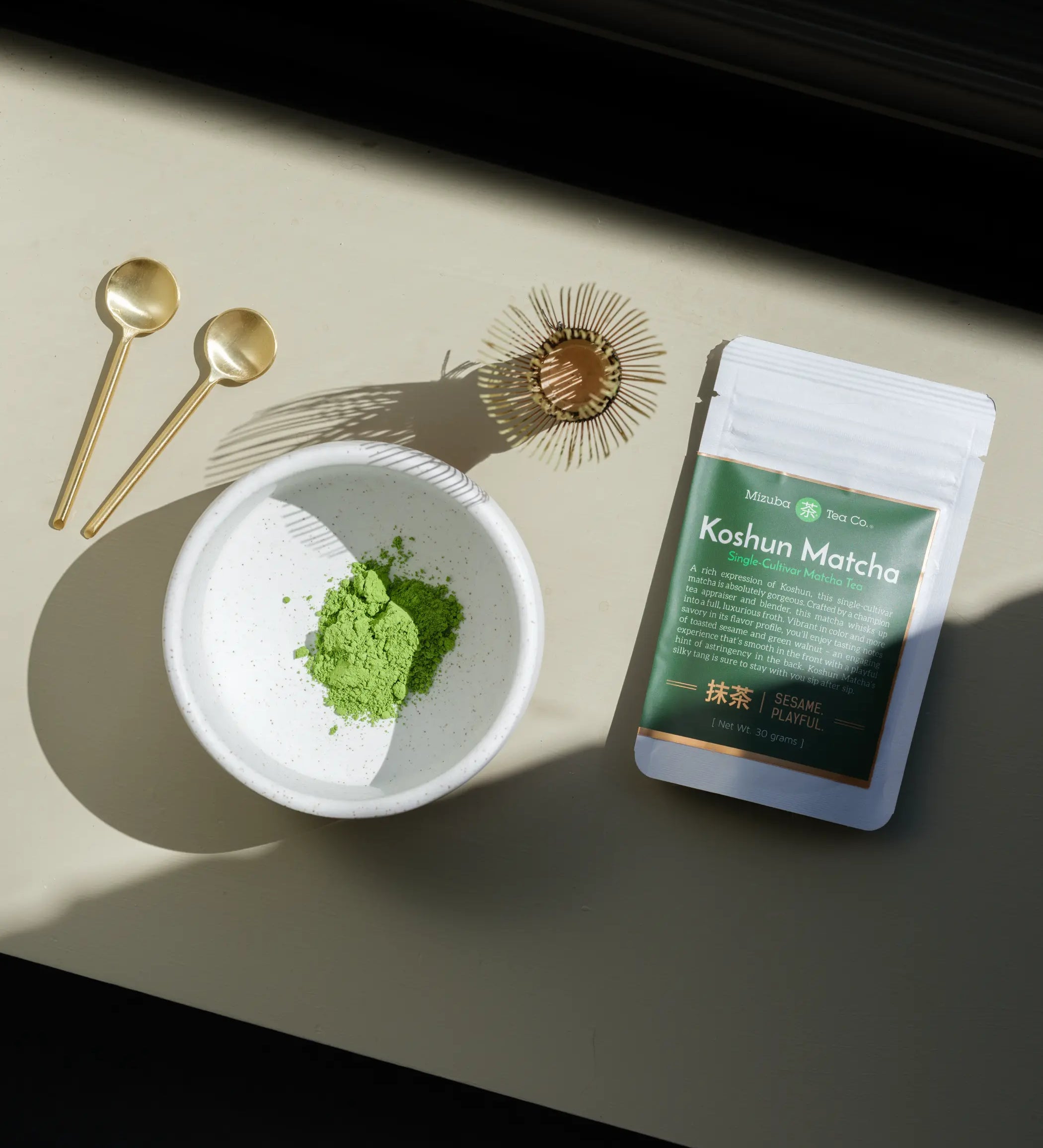 Koshun Matcha powder in a bowl next to a bag of matcha
