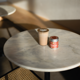 Japanese Hojicha latte on a marble table sitting next to a tin of Mizuba Daily Hojicha