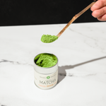 Hinode Matcha green tea powder in a Mizuba container with a chashaku scooping matcha powder.