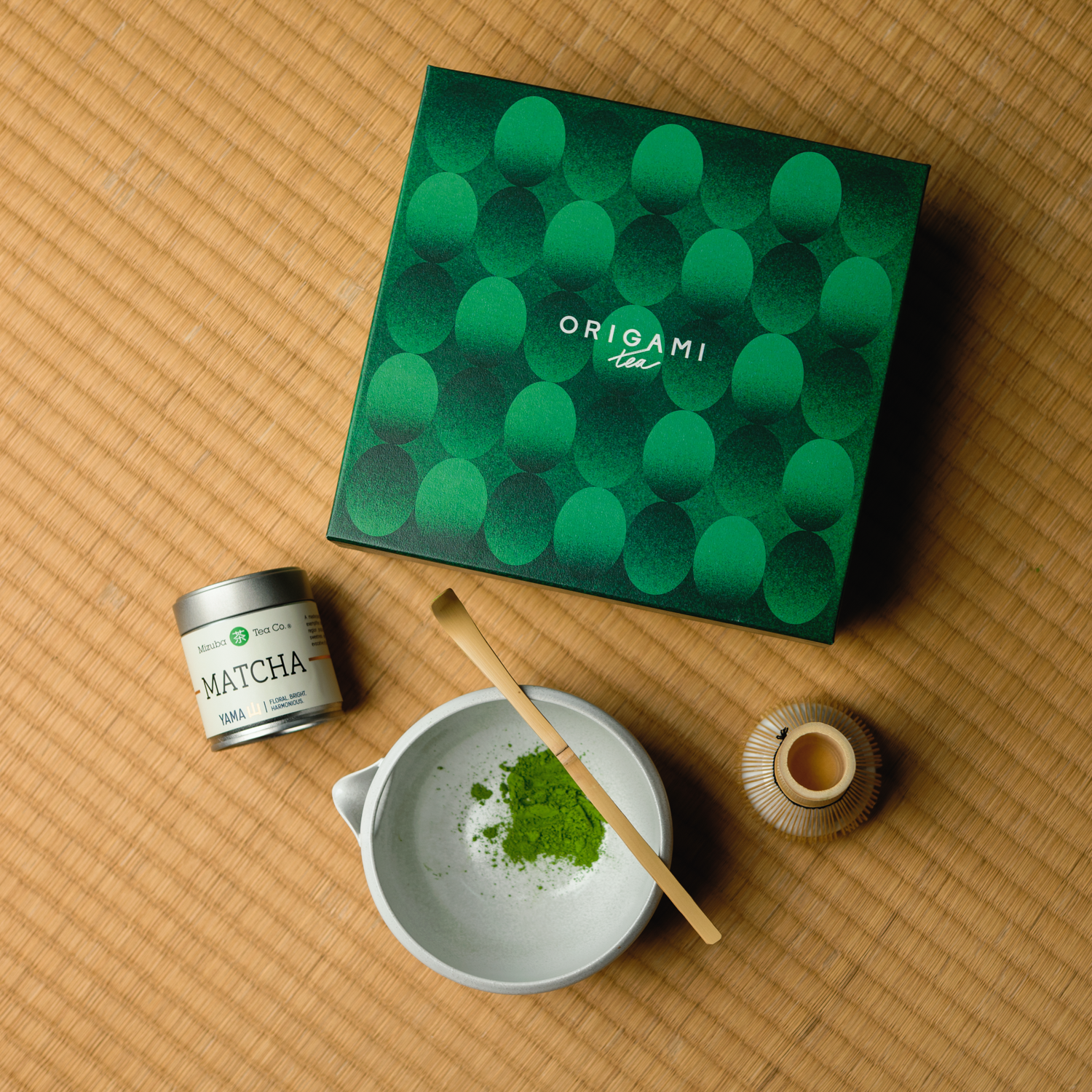 Mizuba Origami Matcha tea set with green  gift box, tin of Yama Mizuba Matcha, whisk, and bowl on a tatami mat surface