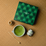 Yama Mizuba Matcha green tea is included in Origami gift set with a box, matcha bowl, whisk, and matcha tea tin on a tatami mat surface.