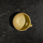 Yellow ceramic chawan matcha bowl by Origami on a dark textured surface