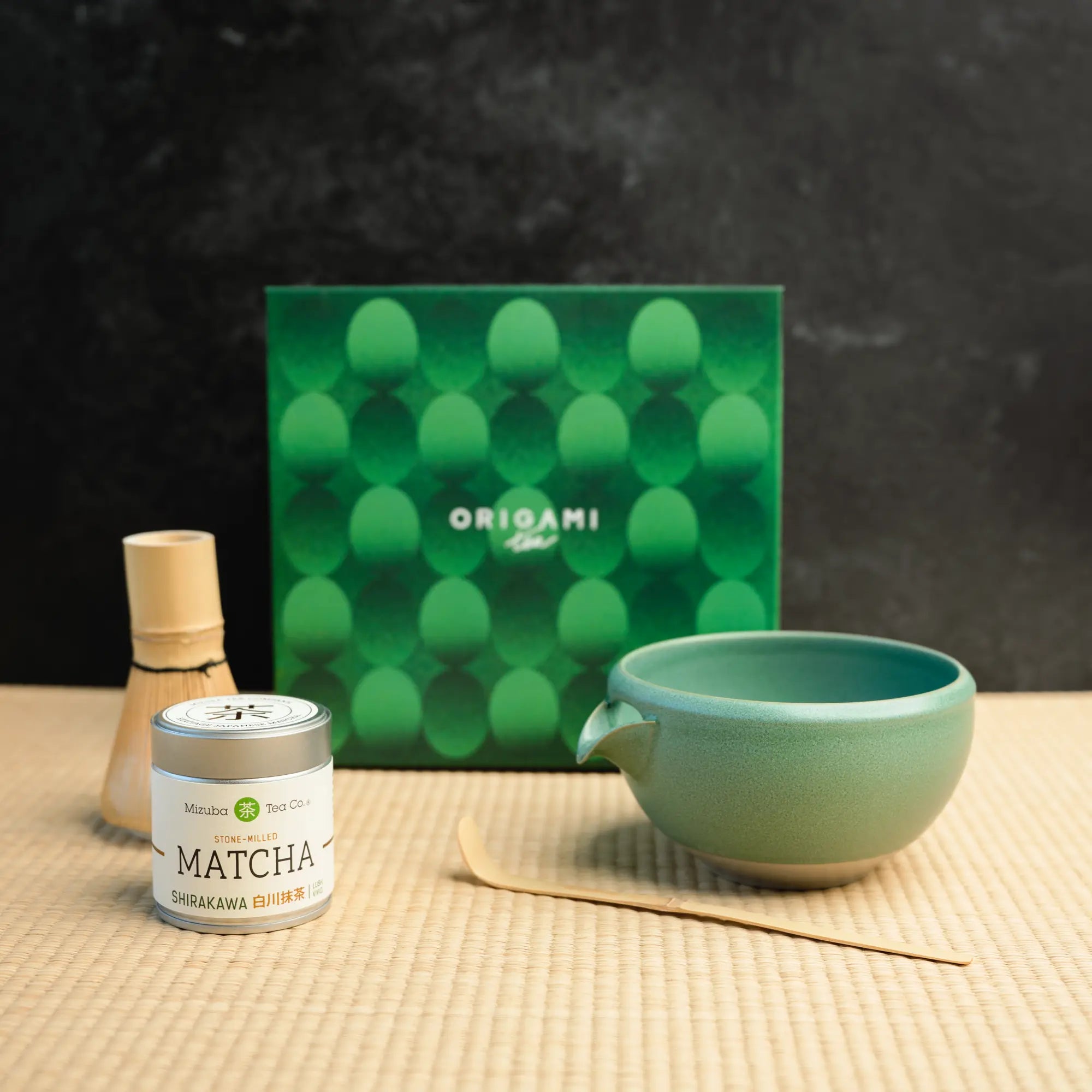 Mizuba Matcha tin next to a chasen, chawan, and matcha bowl