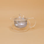 Japanese glass tea pot by Hario sits on a yellow background