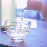 Iced tea is poured from a Hario cold brew bottle into a glass tea cup 