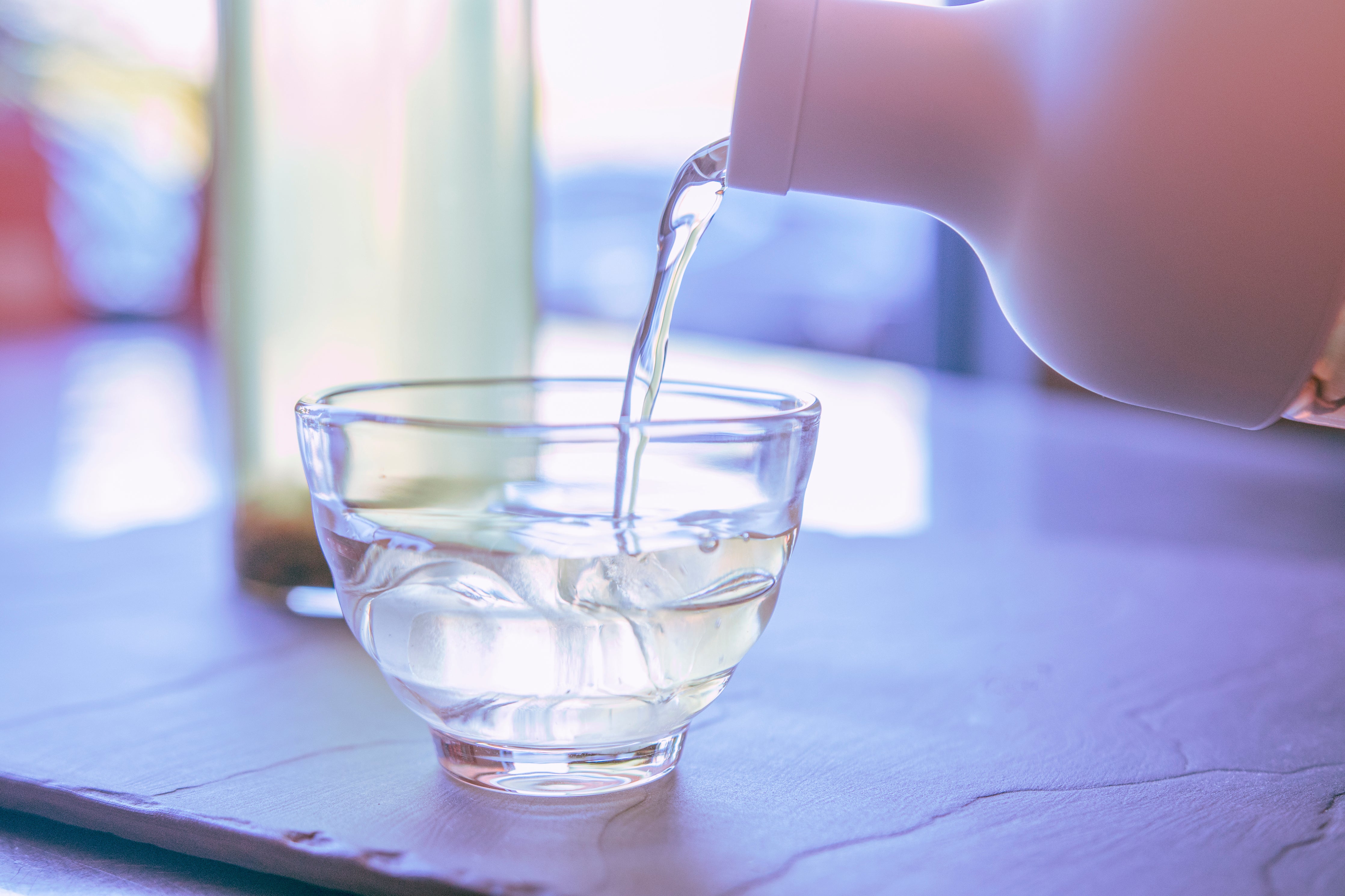 Iced tea is poured from a Hario cold brew bottle into a glass tea cup 