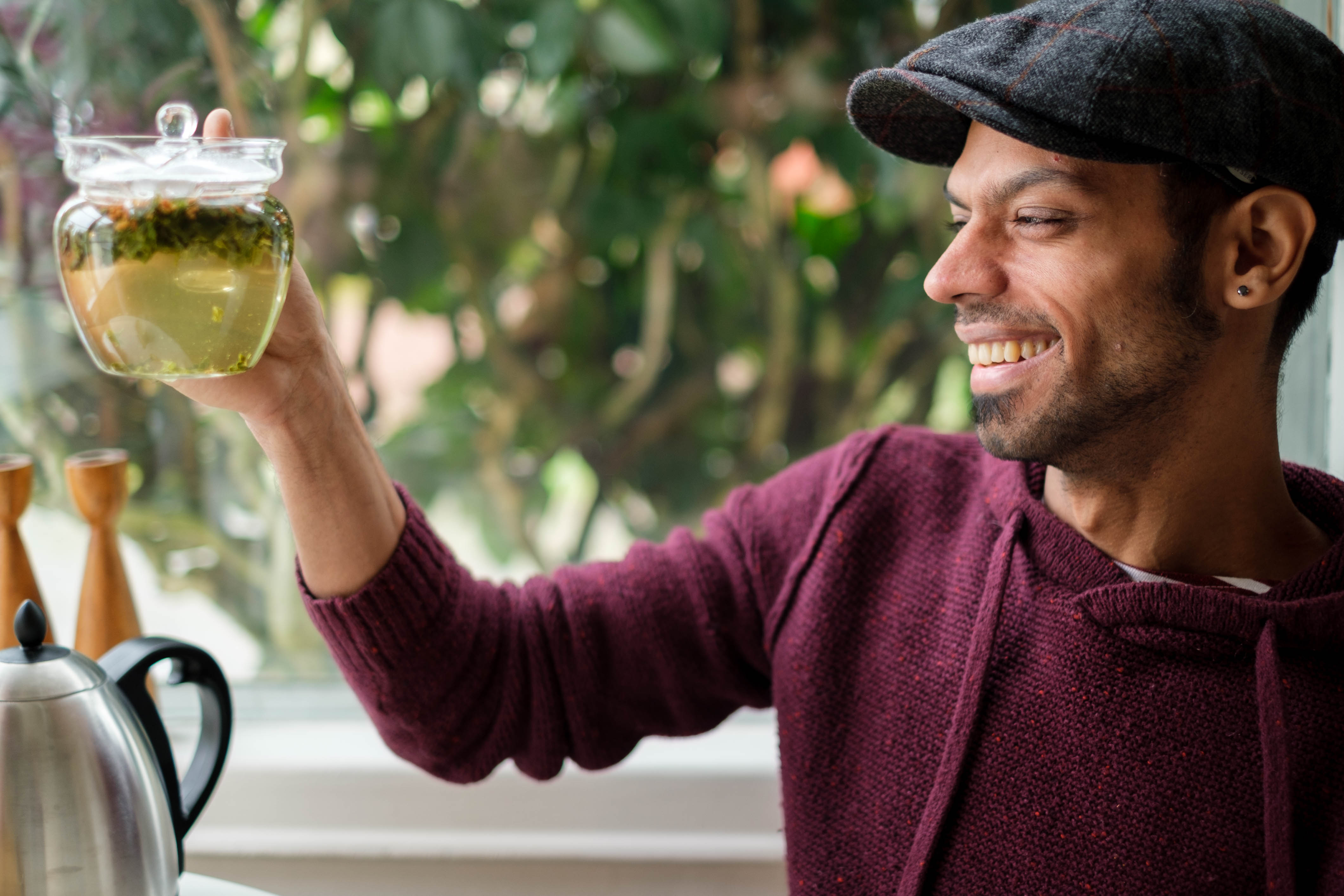 Man smiles looking at a glass teapot of Japanese genmaicha tea.